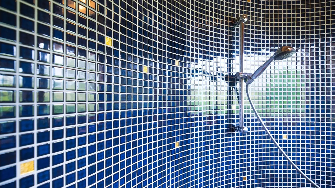 Duschkopf vor blauem Mosaikfliesenspiegel