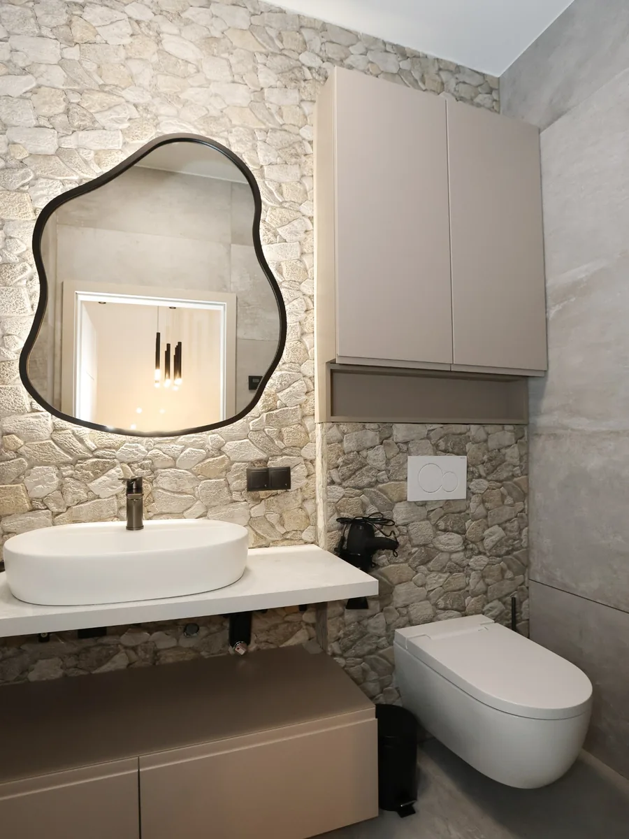Saniertes Badezimmer mit Waschtisch, Wand-WC und Natursteinwand